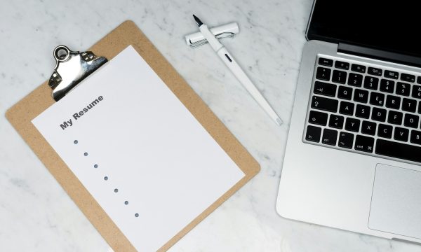 CV posé sur un bureau à côté d’un ordinateur portable
