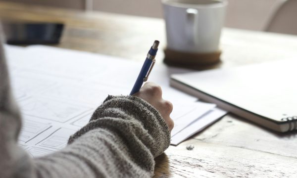 Personne rédigeant une lettre à la main sur un bureau