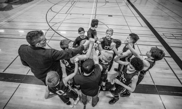 Entraîneur et jeunes sportifs réunis, mains au centre